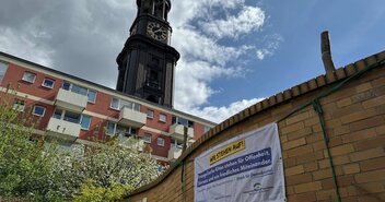 Ein Banner hängt an der Mauer einer Kita. Im Hintergrund ist der Turm der St. Michaelis Kirche in Hamburg zu sehen - Copyright: Christian Schierwagen