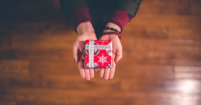 Zwei Hände halten ein Weihnachtsgeschenk