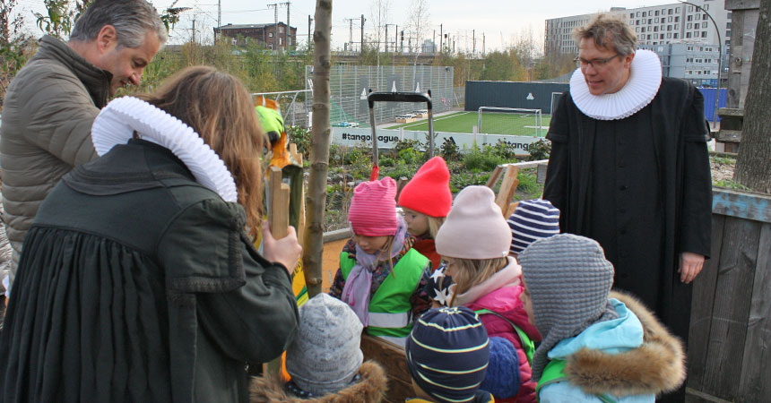 Kinder pflanzen einen Apfelbaum, Pastor Frank Engelbrecht schaut zu